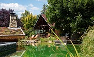 Schwimmteich mit Hütten-Appartment, Foto: visionphotos, Lizenz: Wellnesshotel Seeschlößchen - Privat-SPA &amp; Naturresort