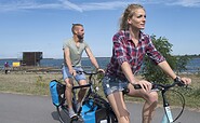 Radfahrer fahren am Schwimmenden Haus am Partwitzer See vorbei, Foto: Nada Quenzel