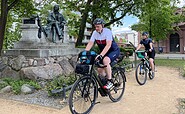 Radler vorm Fontane-Denkmal in Neuruppin, Foto: Thomas Widerin, Lizenz: Tourismusverband Ruppiner Seenland