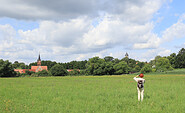 Wanderin betrachtet AR-Kunstwerk auf einer Wiese in Wiesenburg, Foto: Bansen-Wittig