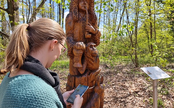 Knobelspaß an der Holzskulptur Gundling, Foto: Sandra Fonarob, Lizenz: Tourismusverband Dahme-Seenland e.V.