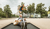 Mann mit Gitarre auf einem Trampolin, dahinter springt ein Mensch, Foto: der bunte hund, Lizenz: der bunte hund