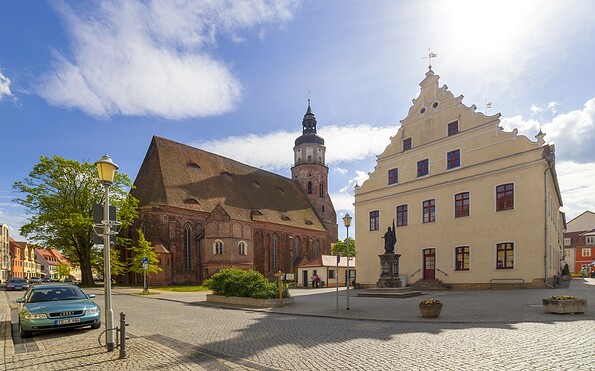 Marktplatz mit Backsteinkirche, hellem Giebelhaus, Statue, Kopfsteinpflaster und blauem Himmel mit Wolken., Foto: Andreas Franke, Lizenz: Andreas Franke