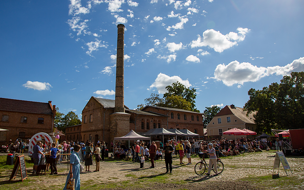 Menschen versammeln sich bei sonnigem Himmel vor historischen Backsteinbauten mit Schornstein auf einem Erntedankfest, Foto: Erste Bernauer Braugenossenschaft e. G., Lizenz: Erste Bernauer Braugenossenschaft e. G.