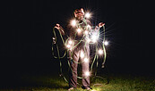 Mann mit Lichterkette bei Nacht auf einer Wiese, Foto: Veronika Zohova, Lizenz: Netzeband Kultur