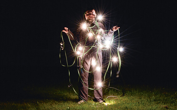 Mann mit Lichterkette bei Nacht auf einer Wiese, Foto: Veronika Zohova, Lizenz: Netzeband Kultur