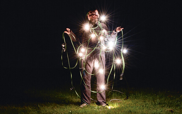 Mann mit Lichterkette bei Nacht auf einer Wiese, Foto: Veronika Zohova, Lizenz: Netzeband Kultur