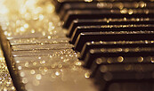 Ausschnitt einer Klaviertastatur mit Zoom auf Tasten mit goldenem Glitzer darauf, Foto: Paul Arky | Unsplash