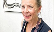 Die Künstlerin steht vor einer weißen Wand und einem ihrer Werke, das japanische Tuschkunst Sumi-e zeigt, Foto: Monika Ruppel, Lizenz: Landhaus Alte Schmiede