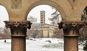Verschneiter Park mit Kirchturm im Hintergrund, gesehen durch leicht unscharfe steinerne Bögen und Säulen im Vordergrund., Foto: André Stiebitz, Lizenz: PMSG