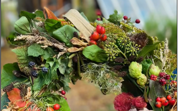 Herbstkranz aus grünen Blättern, roten Beeren, Zapfen, Hopfen und Hortensien, in Händen gehalten., Foto: Nicole Riekeles, Lizenz: Nicole Riekeles