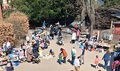 Flohmarkt im Freien mit Ständen für Kleidung und Spielzeug, viele Erwachsene und Kinder auf einem Platz unter Bäumen., Foto: Förderverein Erlöserkita, Lizenz: Förderverein Erlöserkita