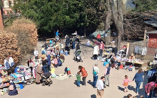 Flohmarkt im Freien mit Ständen für Kleidung und Spielzeug, viele Erwachsene und Kinder auf einem Platz unter Bäumen., Foto: Förderverein Erlöserkita, Lizenz: Förderverein Erlöserkita