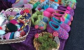 Bunte gefilzte Hausschuhe und Wollaccessoires liegen in Körben und Regalen, daneben rote Fliegenpilz-Deko., Foto: Marlene Prenzel, Lizenz: Marlene Prenzel