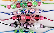 Mehrere bunte Perlenarmbänder mit Glasperlen und Blumenmustern auf farbigen Bändern, auf hellem Hintergrund., Foto: Georg Goes, Lizenz: Museumsverein Glashütte