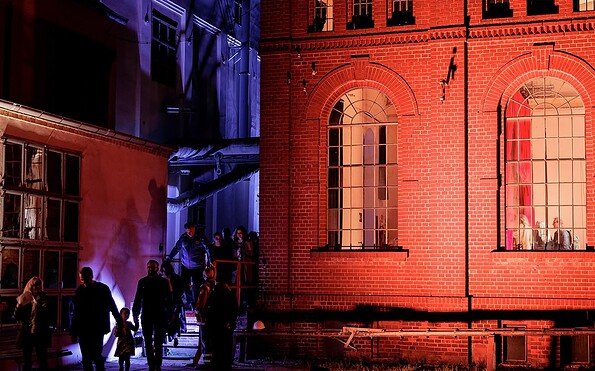 Nachtszene mit rot beleuchtetem Backsteingebäude, blau angestrahlter Fassade und Menschen auf einer Treppe im Hof., Foto: Roxane Adler, Lizenz: Roxane Adler