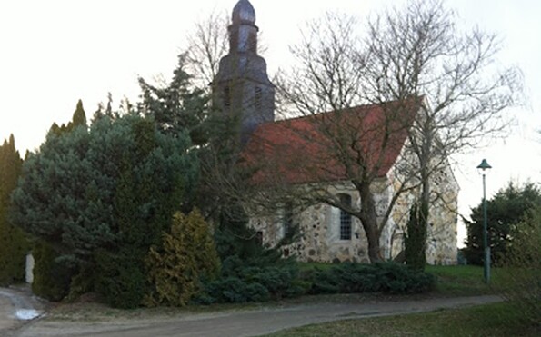 Kirche mit Zwiebelturm und rotem Dach, teils von Bäumen und Sträuchern verdeckt., Foto: TVEEL, Lizenz: TVEEL